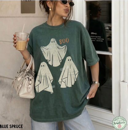 Person wearing a green t-shirt with ghost designs and holding a drink.