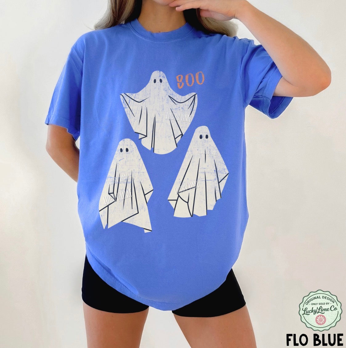 Person wearing a blue t-shirt with ghost designs and 'BOO' text on a plain background