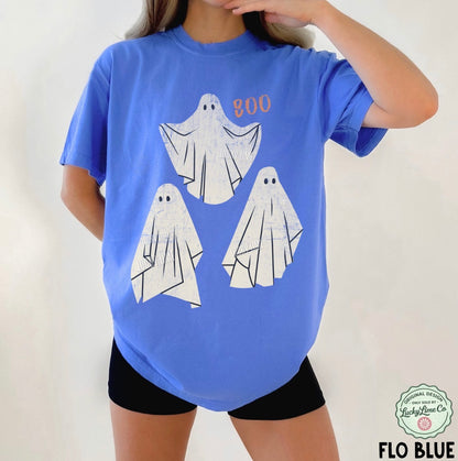 Person wearing a blue t-shirt with ghost designs and 'BOO' text on a plain background