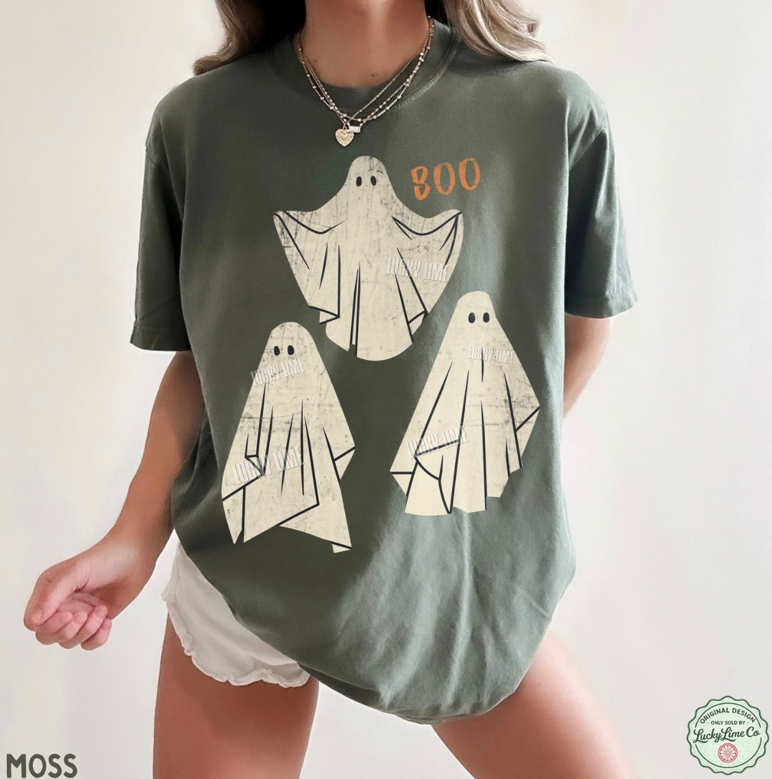 Person wearing a green t-shirt with ghost designs and 'BOO' text on a plain background