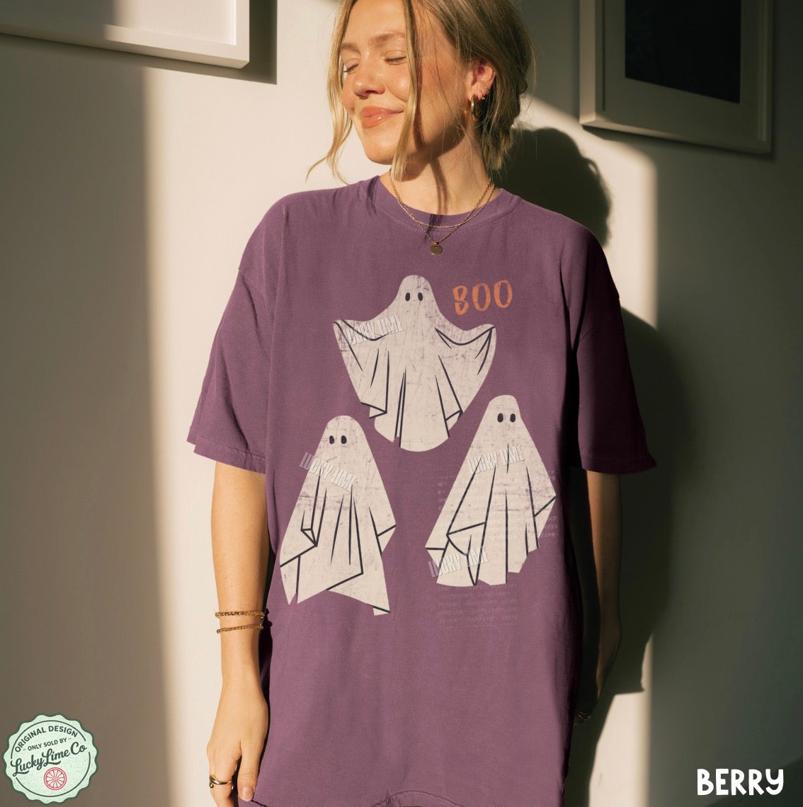 Person wearing a purple t-shirt with ghost designs and 'BOO' text, standing against a neutral wall.
