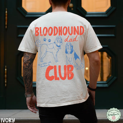Person wearing a t-shirt with 'Bloodhound Dad Club' design on the back, standing in front of a door.