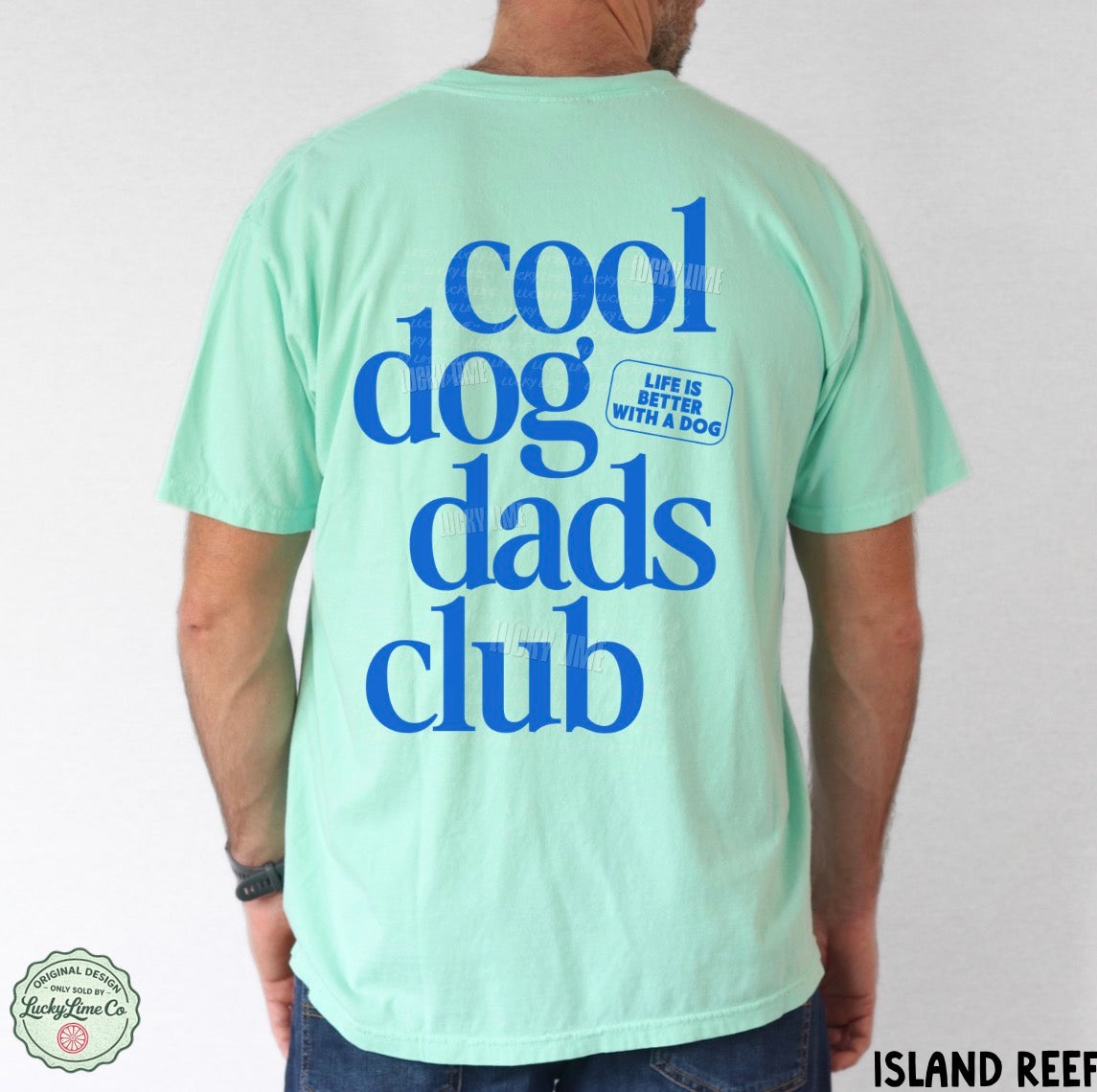 Person wearing a light green t-shirt with 'cool dog dads club' text on the back, against a plain background.
