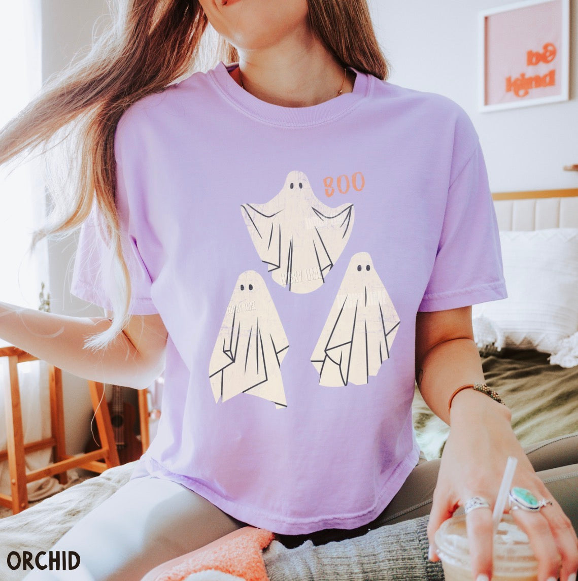 Person wearing a purple t-shirt with ghost designs, sitting in a room.