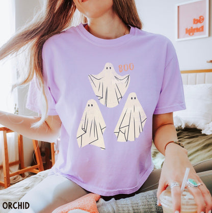 Person wearing a purple t-shirt with ghost designs, sitting in a room.