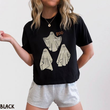 Person wearing a black t-shirt with ghost designs and 'BOO' text, paired with gray shorts on a plain background.