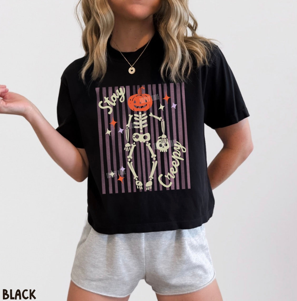Person wearing a black t-shirt with a Halloween skeleton design and gray shorts on a white background