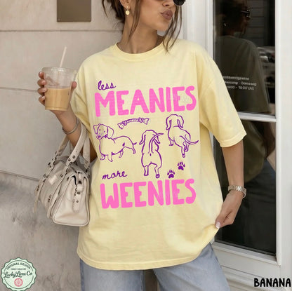 Person wearing a yellow t-shirt with pink text and graphics, holding a drink.
