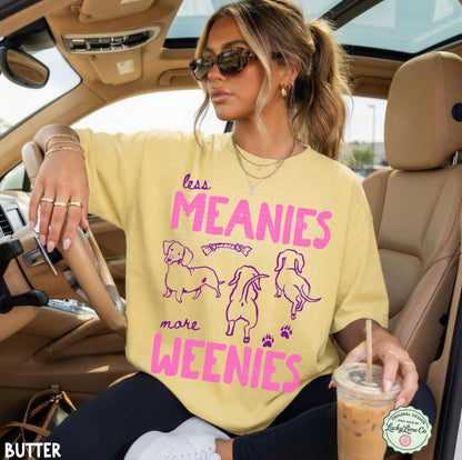 Woman sitting in a car wearing a yellow t-shirt with a humorous print, holding a drink.