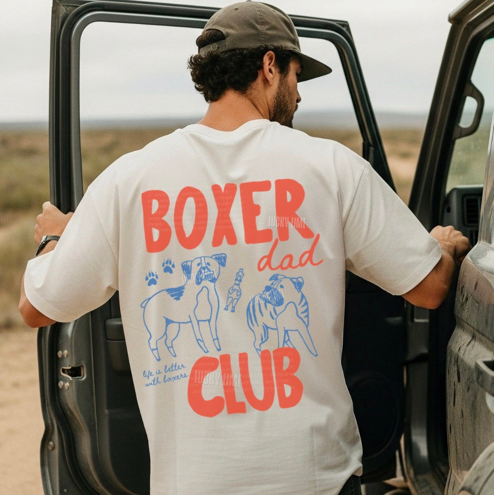 Man wearing a 'Boxer Dad Club' t-shirt getting into a car in a desert setting.