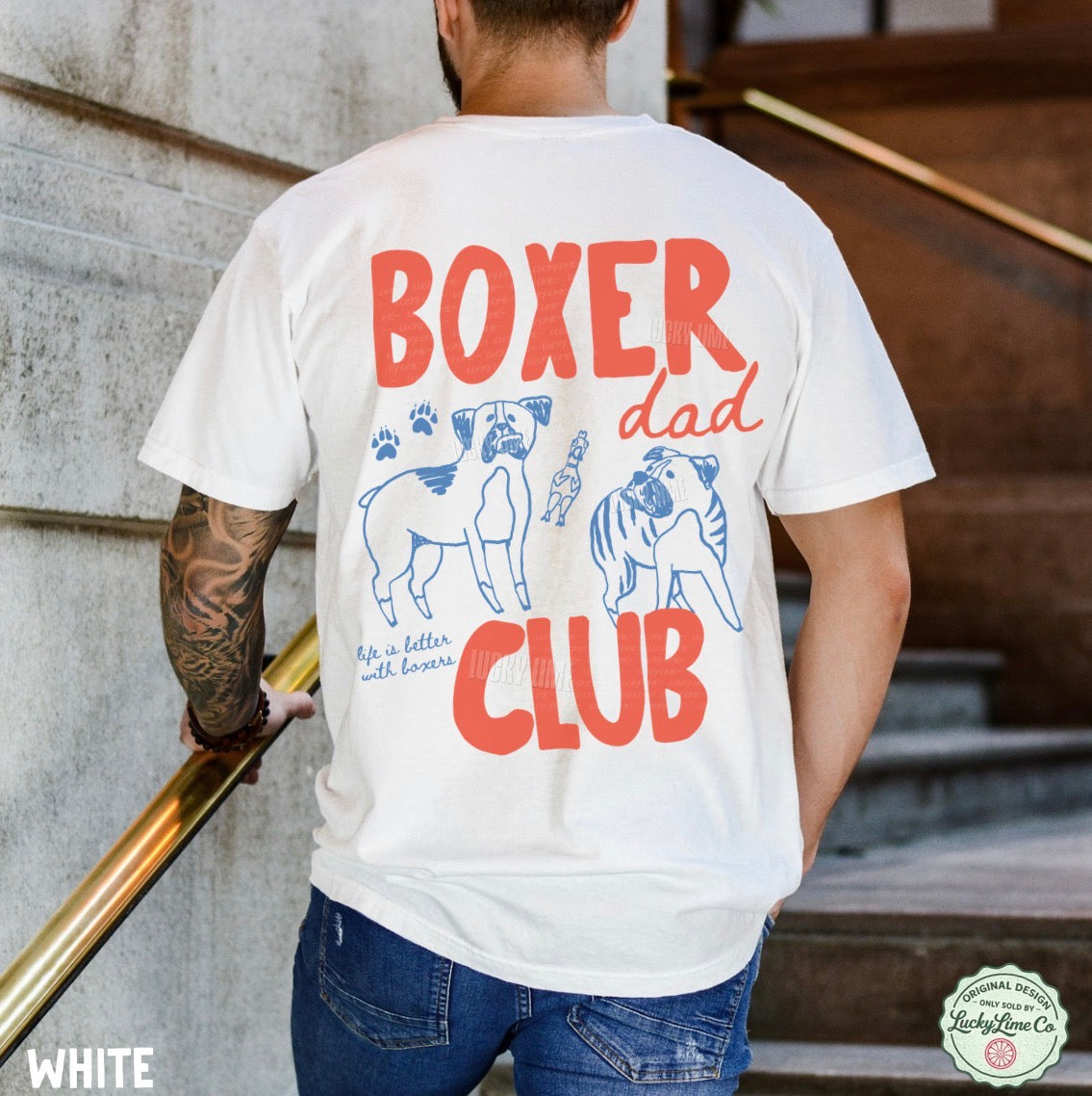 Person wearing a white t-shirt with 'Boxer Dad Club' design and tattoos on arm.