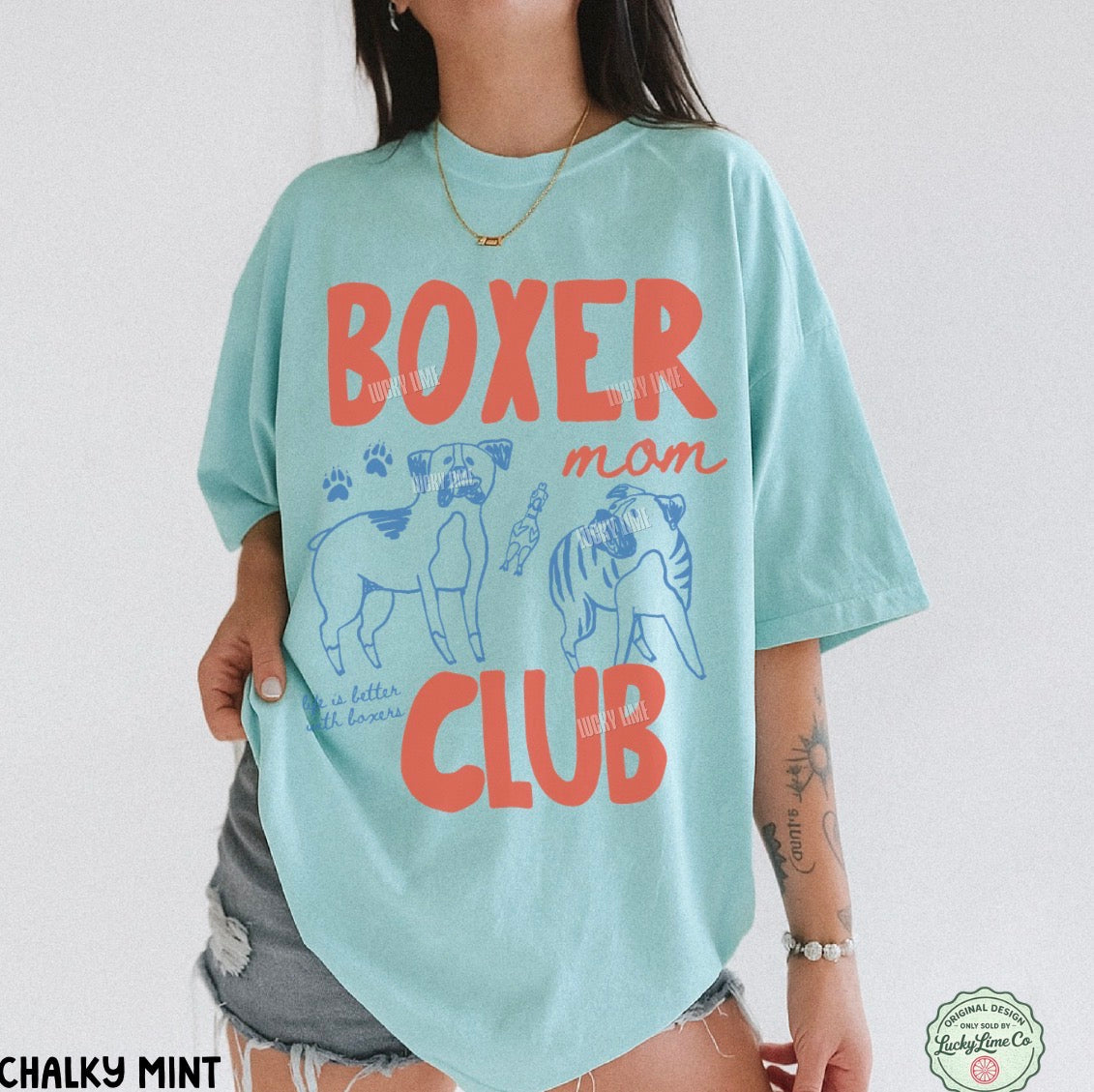 Person wearing a light blue t-shirt with 'Boxer mom club' text and graphics on a white background