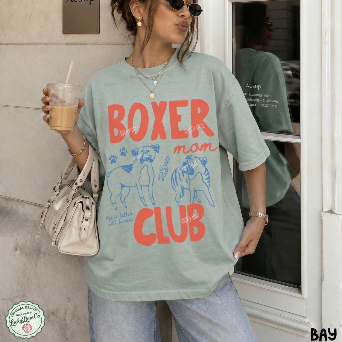 Person wearing a 'French Bulldog Mom' t-shirt holding a drink.