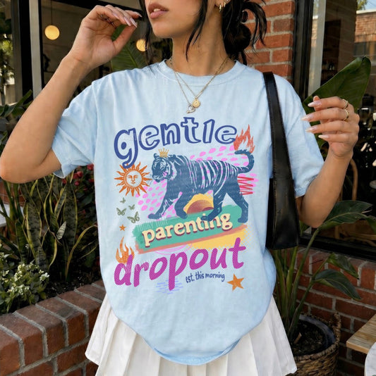 Person wearing a light blue t-shirt with colorful graphics and text, standing outdoors.