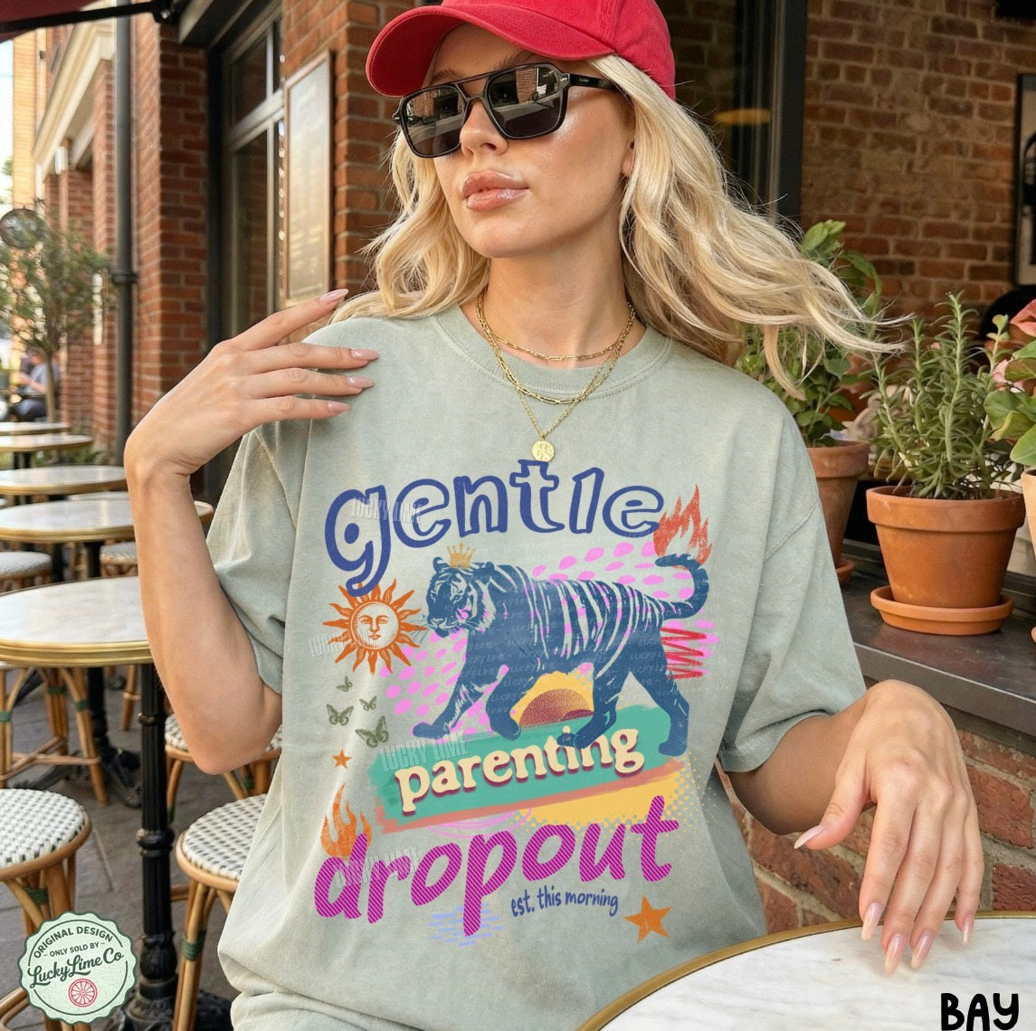 Woman wearing a t-shirt with a colorful graphic and text in an outdoor setting.