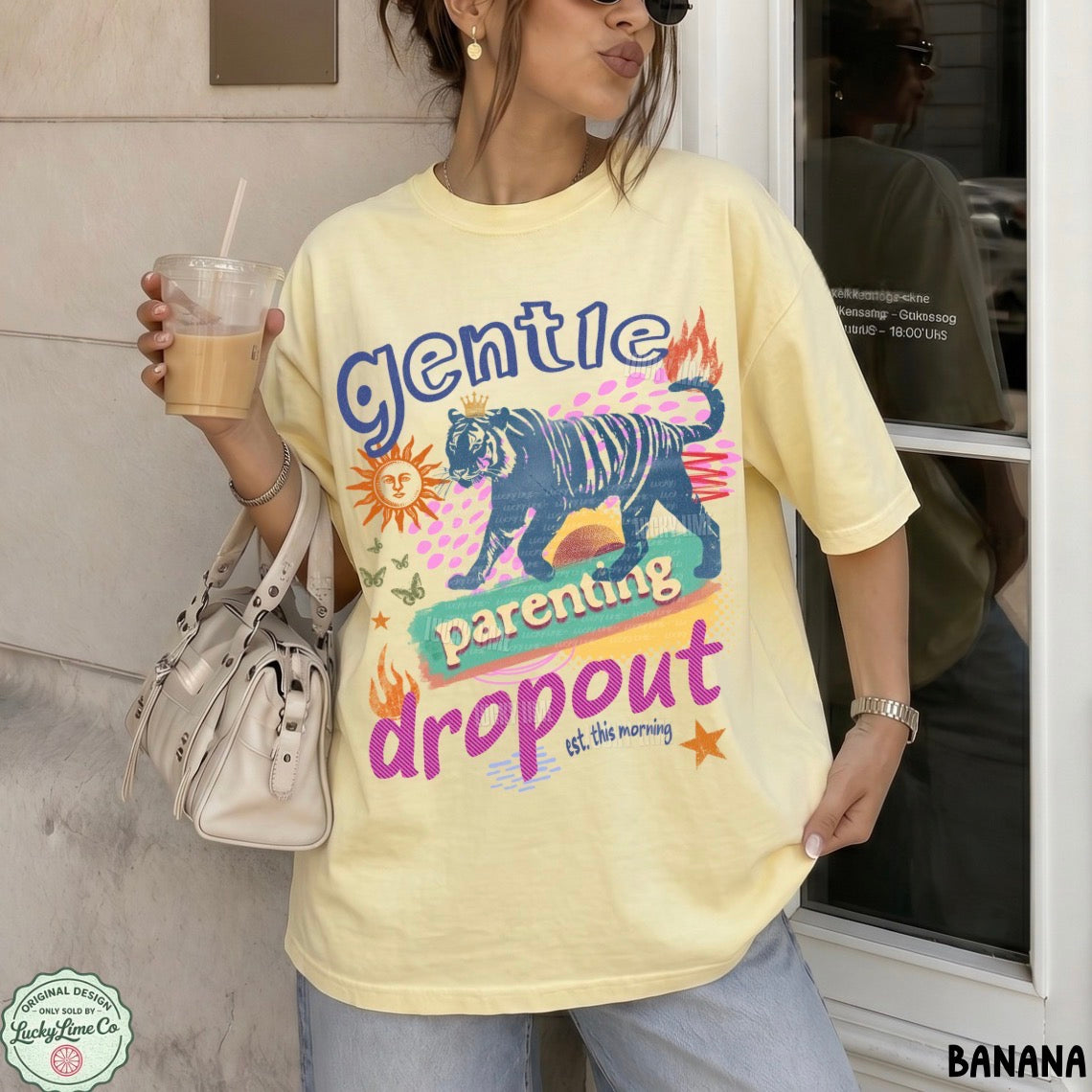 Person wearing a yellow t-shirt with a graphic design and text, holding a drink.
