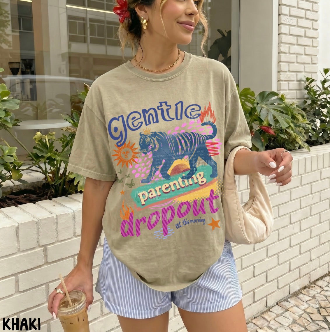 Woman wearing a 'gentle parenting dropout' t-shirt with a tiger graphic, standing outdoors.