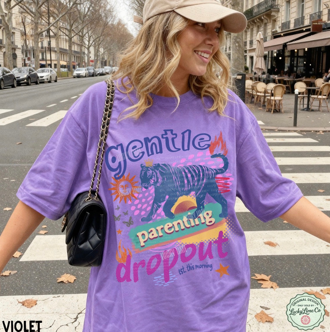 Woman wearing a purple t-shirt with graphic design and text, standing on a street.