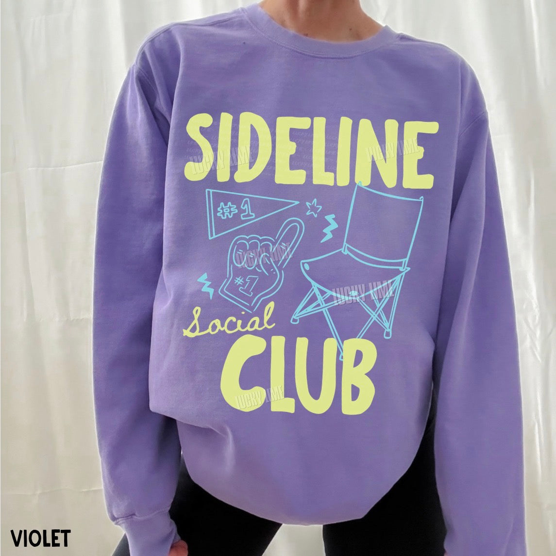 Purple sweatshirt with 'Sideline Social Club' text and graphics on a white background
