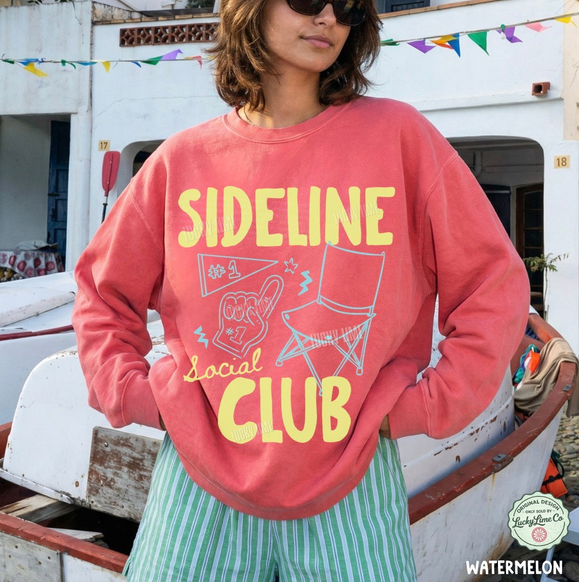 Person wearing a pink sweatshirt with 'Sideline Social Club' text and graphics, standing on a boat.