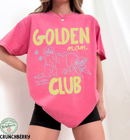 Person wearing a pink t-shirt with 'Golden Mom Club' text and graphics on a white background