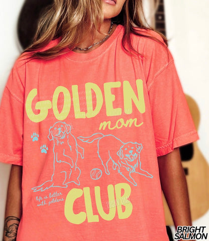 Person wearing a coral t-shirt with 'Golden Mom Club' text and graphics.
