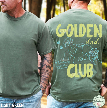 Two men wearing light green t-shirts with 'GOLDEN dad CLUB' text and dog illustrations in a forest setting.