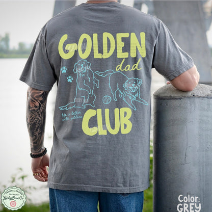 Person wearing a gray t-shirt with 'Golden Dad Club' design outdoors.