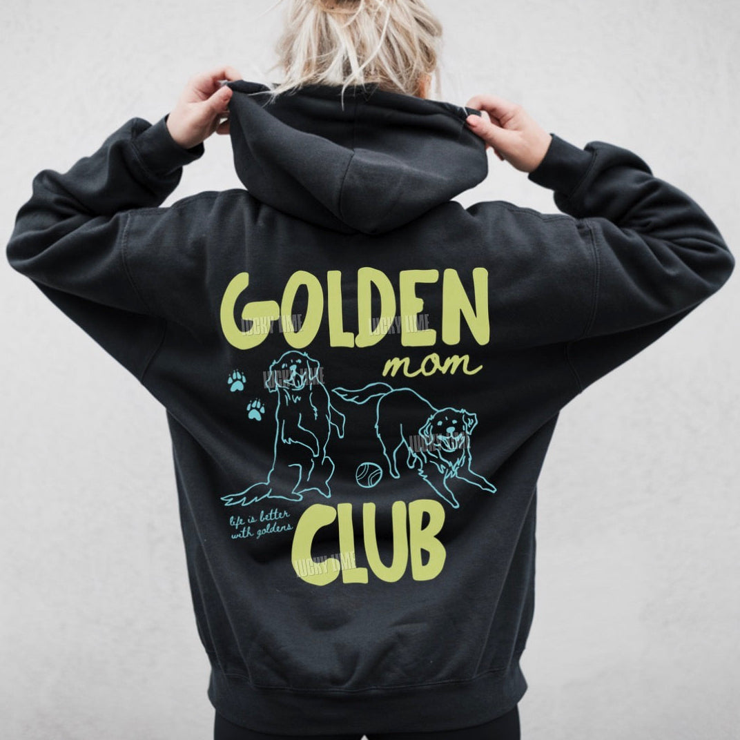 Black hoodie with 'Golden Mom Club' text and dog illustration on the back, worn by a person.
