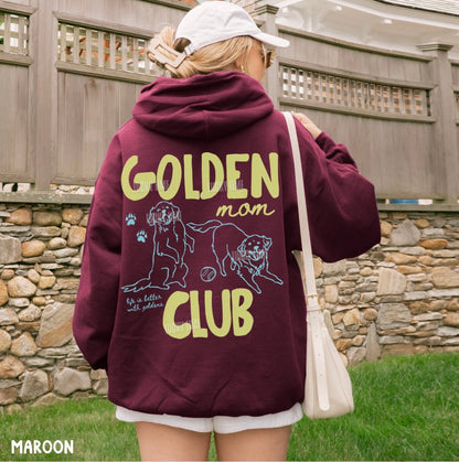Person wearing a maroon hoodie with 'Golden Man Club' text and dog illustration, standing outdoors.