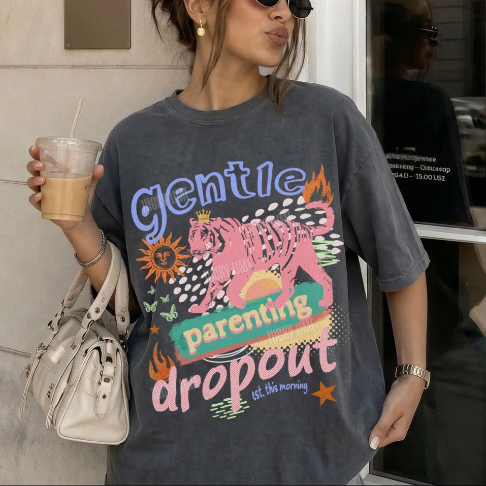 Person wearing a graphic t-shirt with colorful text and design, holding a drink and a bag.