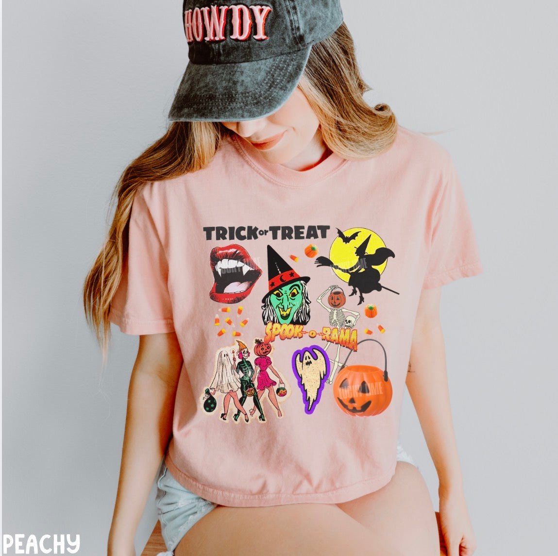 Person wearing a pink Halloween-themed t-shirt with graphics and a 'HOWDY' cap.