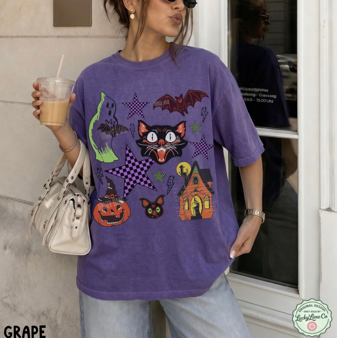 Person wearing a purple Halloween-themed t-shirt with various graphics, holding a drink.