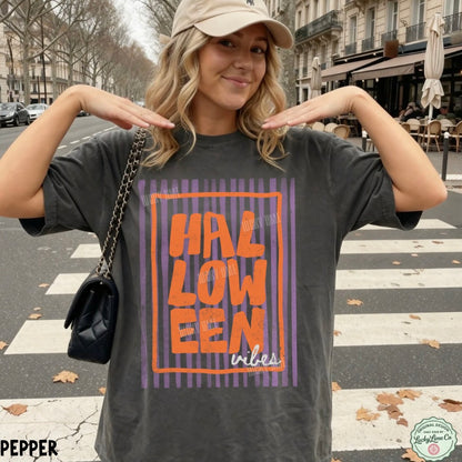 Woman wearing a 'HALLOWEEN vibes' t-shirt on a city street.