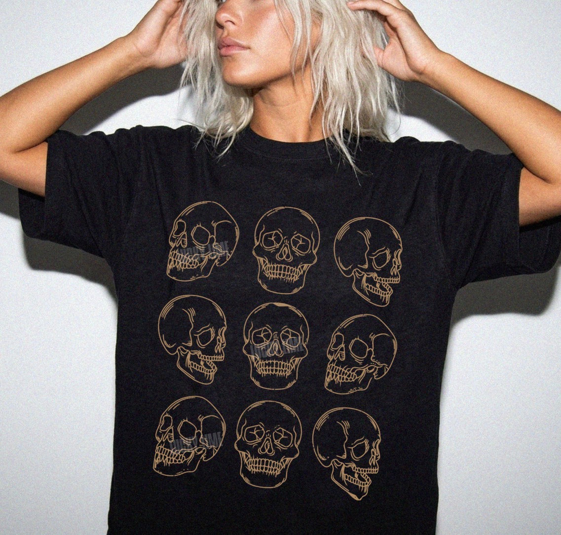 Person wearing a black t-shirt with gold skull designs on a plain background