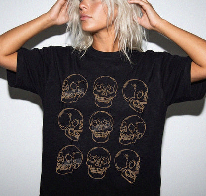 Person wearing a black t-shirt with gold skull designs on a plain background