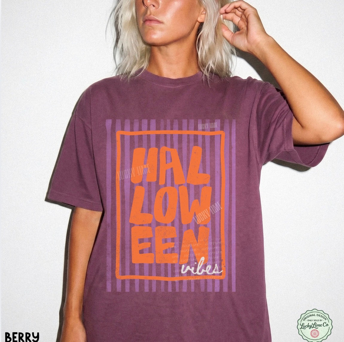 Person wearing a berry colored  t-shirt with 'HALLOWEEN vibes' in orange text on a white background