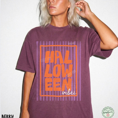 Person wearing a berry colored  t-shirt with 'HALLOWEEN vibes' in orange text on a white background