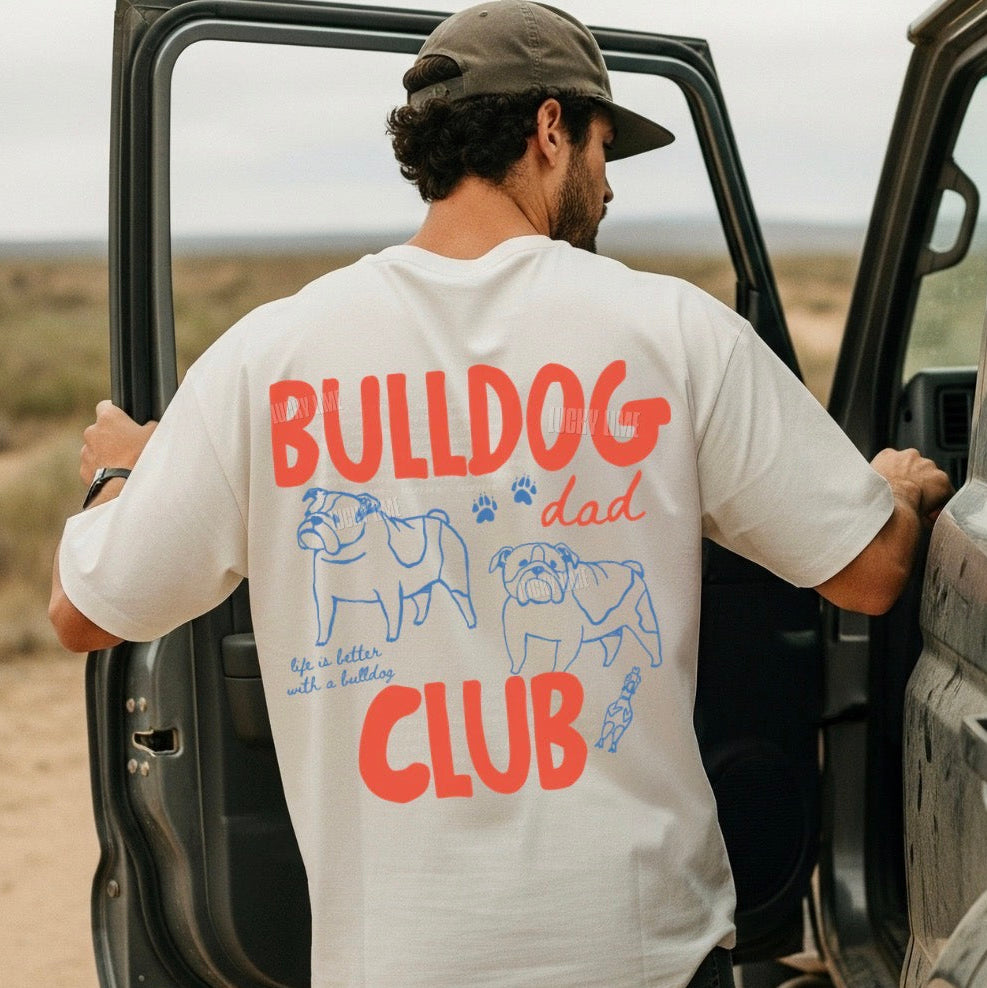 Man wearing a 'Bulldog Dad Club' t-shirt getting into a car in a desert setting.