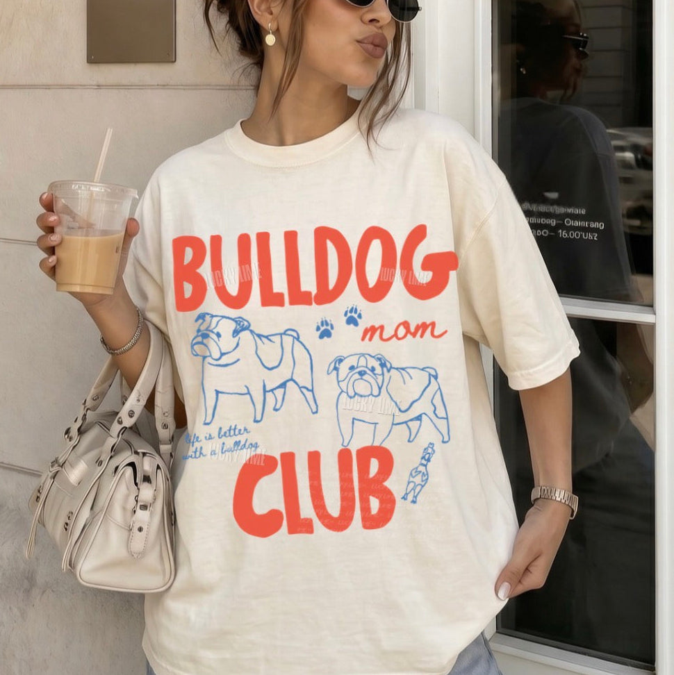 Person wearing a 'Bulldog Mom Club' t-shirt holding a drink.