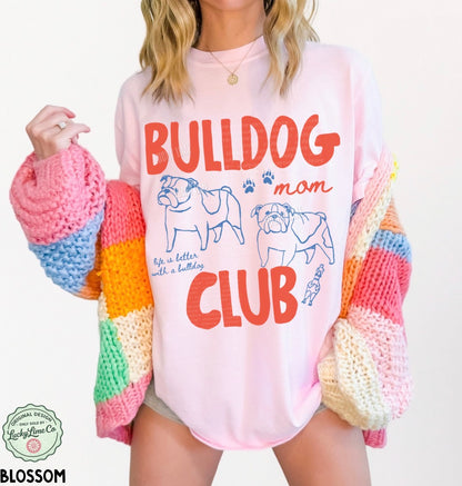 Person wearing a pink shirt with 'Bulldog Mom Club' text and graphics, paired with a colorful sweater.
