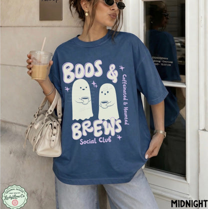 Person wearing a blue t-shirt with ghost graphics and text, holding a drink.