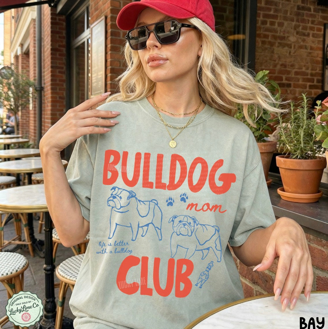 Woman wearing a t-shirt with 'Bulldog Mom Club' design outdoors.
