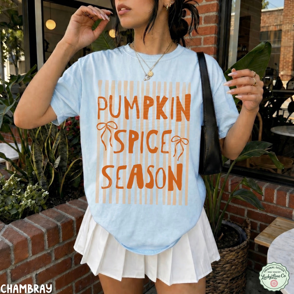 Person wearing a light blue t-shirt with 'Pumpkin Spice Season' text in an outdoor setting.