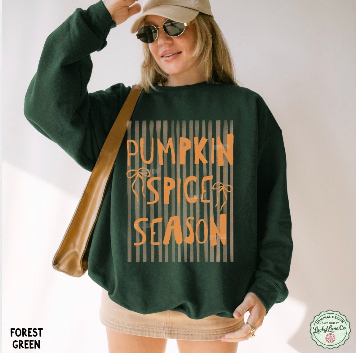 Person wearing a green sweatshirt with 'Pumpkin Spice Season' text, holding a brown bag.
