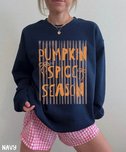 Person wearing a navy sweatshirt with 'Pumpkin Spice Season' text and pink checkered shorts.