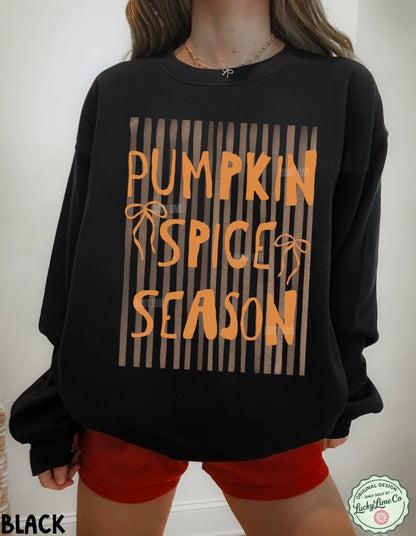 Black sweatshirt with 'Pumpkin Spice Season' text worn by a person, on a plain background.
