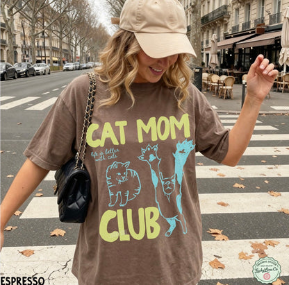 Woman wearing a 'Cat Mom Club' t-shirt on a city street.