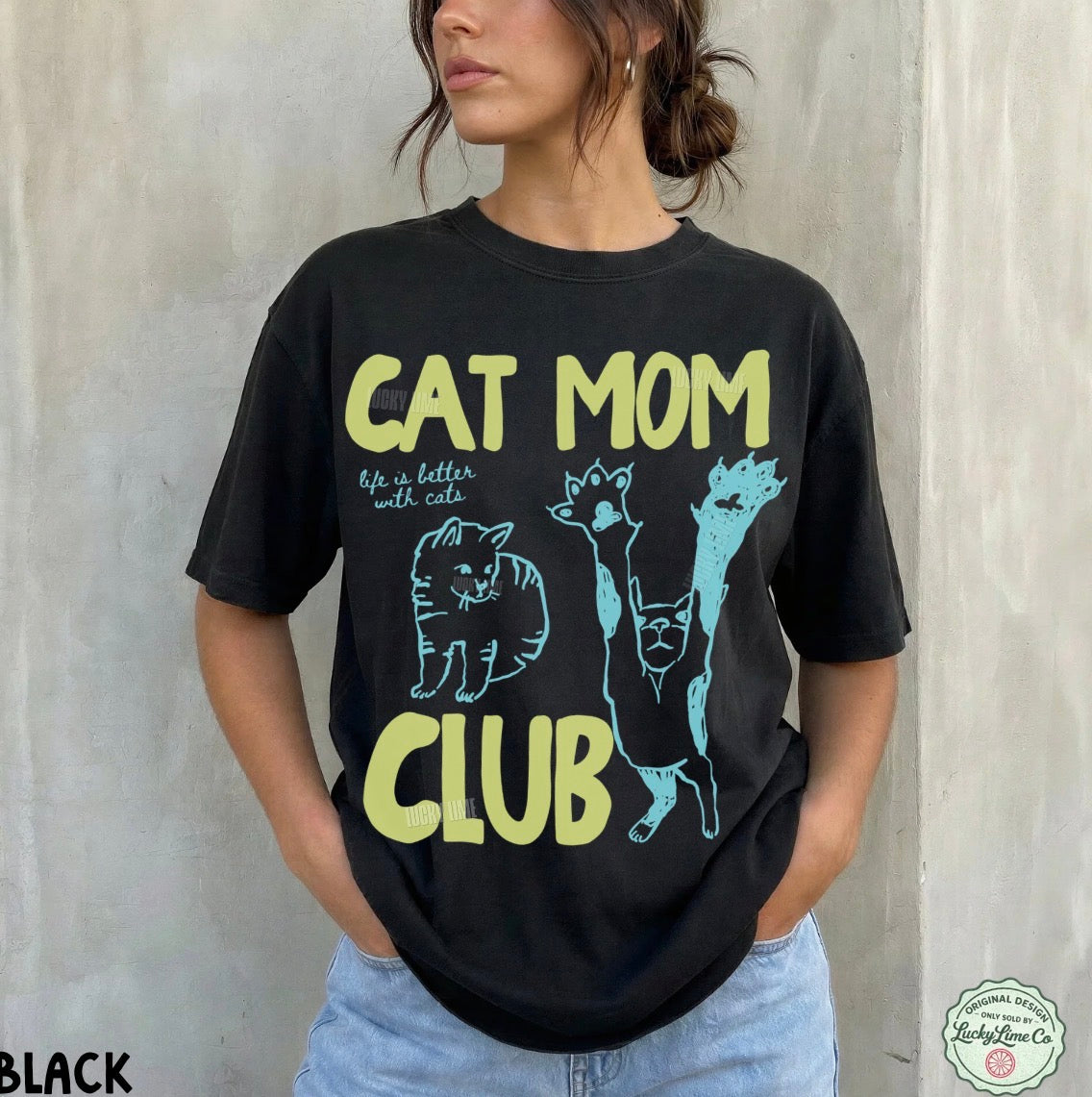 Person wearing a black t-shirt with 'Cat Mom Club' text and cat illustrations against a plain background.