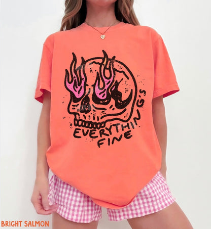 Person wearing a bright salmon t-shirt with a skull design and text, paired with pink checkered shorts.